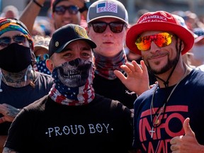 In this file photo taken on October 29, 2020 Supporters wearing Proud Boy clothing wave to the camera during a Make America Great Again campaign rally in Tampa, Florida.