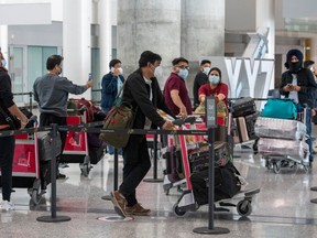 Passengers from Air India flight 187 from New Delhi wait for their transportation to quarantine after arriving at Pearson Airport in Toronto on Wednesday, April 21, 2021.