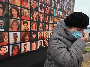 A woman cries in front of a huge screen bearing portraits of late crew members and passengers of Ukraine International Airlines Flight 752, which crashed in Iran a year before, during a commemorative ceremony on January 8, 2021 at the site of a future memorial on the Dnipro river bank in Ukraine's capital Kiev.