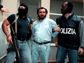Anti-Mafia police wearing masks to hide their identity, escort top Mafia fugitive Giovani Brusca May 21 as he leaves Palermo's police headquarters to be taken to a maximum security prison.