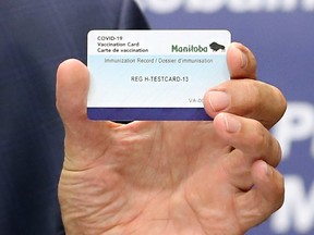Premier Brian Pallister holds a vaccination card during a press briefing on vaccine measures at the Manitoba Legislative Building in Winnipeg on Tues., June 8, 2021.