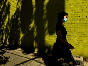 A person walks past a colourful wall while wearing a protective mask in the warm weather during the COVID-19 pandemic in Toronto on Wednesday, June 16, 2021.