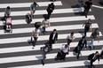 Pedestrians walk cross an intersection in Tokyo, Japan, on Tuesday, May 24, 2016. Japan's service producer price index (PPI) figures are scheduled to be released on May 26, 2016.