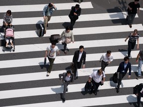 Pedestrians walk cross an intersection in Tokyo, Japan, on Tuesday, May 24, 2016. Japan's service producer price index (PPI) figures are scheduled to be released on May 26, 2016.