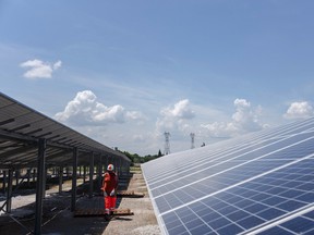 A construction worker passes between solar panels at the Renewable Energy Systems Ltd. solar park, on a brownfield site formerly occupied by an ArcelorMittal SA metals plant, during construction in Laudun L'Ardoise, France, on Wednesday, June 9, 2021. EU member states will put more than 34 billion euros of stimulus into clean energy, including renewable power projects, grid upgrades, and renewable hydrogen deployment, according to recovery plans submitted to the European Commission.