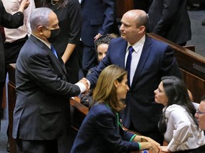 Israel's outgoing prime minister Benjamin Netanyahu (left) shakes hands with his successor (right), incoming Prime Minister Naftali Bennett, after a special session to vote on a new government at the Knesset in Jerusalem, on June 13, 2021.