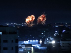 Explosions light-up the night sky above buildings in Gaza City as Israeli forces shell the Palestinian enclave, early on June 16.