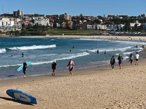 Beachgoers walk along the sand at Bondi Beach in Sydney June 27, 2021, on the first full day of a two-week COVID-19 lockdown to contain an outbreak of the highly contagious Delta variant.