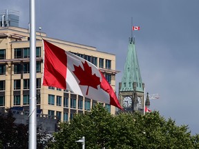 A flag flies at half-mast in Ottawa on June 28, 2021, in mourning for the children whose remains were found in unmarked graves on the grounds of former Indian residential schools. There are additional reasons this will be a subdued Canada Day, writes Raymond J. de Souza.