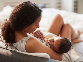 Mother breastfeeding baby at home
