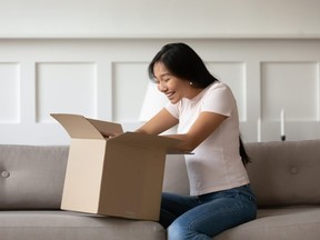 woman sitting on couch in living room opens received delivered parcel feels happy. Satisfied client shopper buy qualified goods in internet unbox package, quick trusted delivery service concept