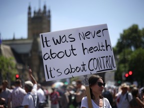 A woman holds a placard during an anti-lockdown and anti-vaccine protest, amid the coronavirus disease (COVID-19) pandemic, near the Houses of Parliament, London, Britain, June 14, 2021.