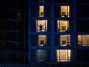 A person closes the curtains in a room at a government-authorized COVID-19 quarantine hotel in Richmond, B.C., on Feb. 28, 2021.