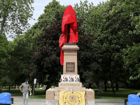 A statue of Sir John A. Macdonald, Canada's first prime minister, stands covered after a protest over residential school issues at City Park in Kingston on June 11, 2021.