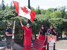 REGINA, SASK: June 5, 2020 - One person waves a flag while others stand by during at a rally for Missing and Murdered Indigenous Women and Girls, held at the Saskatchewan Legislative building on June 5, 2020.