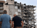 eople look at a portion of the 12-story Champlain Towers South condo building that partially collapsed on June 24, 2021 in Surfside, Florida.
