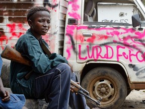 August 2003 shows fourteen-year-old child soldier resting in the Viatown street of Monrovia