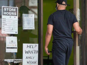 A man enters a restaurant displaying a help wanted sign on Toronto’s Bloor Street West on June 9, 2021.