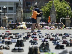 People embrace in front of the Centennial Flame on Parliament Hill on June 4, 2021, at a memorial for the 215 children whose remains were found at the grounds of the former Kamloops Indian Residential School at Tk’emlups te Secwépemc First Nation in Kamloops, B.C.