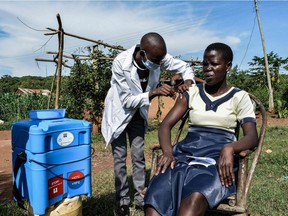A health worker administers the AstraZeneca vaccine to a woman as part of a door-to-door campaign to deliver the vaccines to people who live far from medical facilities in Siaya, Kenya, on May 18, 2021.