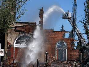 A firefighter douses the remains of St. Jean Baptiste Parish church in Morinville, Alta., which burned to the ground on June 30, 2021.