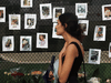A woman walks by photos of missing people on June 25, 2021 in Surfside, Florida. According to reports, after the collapse of the 12-story Champlain Towers South condo building on June 24, more than 150 people have been reported as missing.