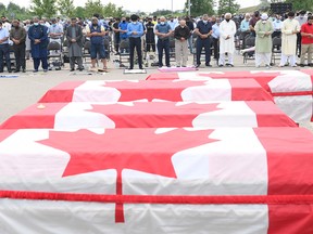 Mourners pray as caskets draped in Canadian flags are lined up at a funeral for the four Muslim family members killed in a deadly vehicle attack on June 6, 2021, in London, Ont. Talat Afzaal, 74, her son Salman Afzaal, 46, his wife Madiha Salman, 44, and their 15-year-old daughter Yumna Afzaal all died when they were struck by a driver in what officials have deemed a terror attack.