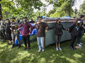 Supporters link arms protecting a momeless encampment at Trinity Bellwoods Park in Toronto, Ont. on Tuesday June 22, 2021.