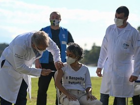 Brazil's Health Minister Marcelo Queiroga (L) gives a dose of the covid-19 vaccine on the first day of the mass vaccination rollout on June 20, 2021.