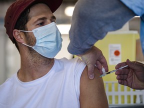 A cyclist receives a dose of the Pfizer-BioNTech COVID-19 vaccine at the Gilles Villeneuve racetrack in Montreal, on Saturday, May 29, 2021.