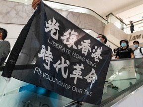 A pro-democracy supporter holds a "Liberate Hong Kong. Revolution of Our Time" flag during a rally at a shopping mall on May 25, 2020, in Hong Kong, China.