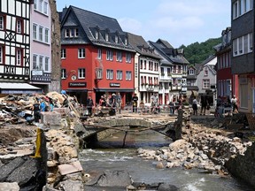 General view shows residents forming a human chain to clear debris piece by piece on a stone bridge in the center of the flood-ravaged spa town Bad Munstereifel, North Rhine-Westphalia state, western Germany, on July 20, 2021. - The German government on July 19, 2021 pledged to improve the country's under-fire warning systems as emergency services continued to search for victims of the worst flooding in living memory, with at least 165 people confirmed dead.