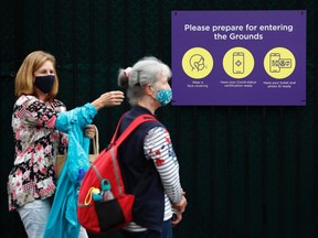 Spectators wait beside a sign in reference to COVID-19 as they queue outside Wimbledon before the start of play June 28, 2021 in London, England.
