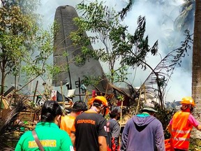 In this handout photo taken on July 4, 2021, and received from the Philippine military Joint Task Force-Sulu (JTF-Sulu), rescue workers arrive as smoke billows from the wreckage of a Philippine Airforce C-130 transport plane after it crashed near the airport in Jolo town, Sulu province on the southern island of Mindanao.
