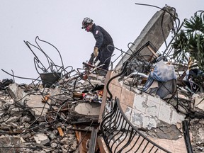 After a brief stop to demolish the standing debris, search-and-rescue personnel continue to work in the rain on the rubble pile of Champlain Towers South.