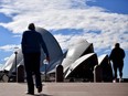 This picture taken on June 26, 2021, shows people walking in front of the Opera House, usually packed with visitors, as a lockdown in Australia's largest city Sydney was tightened on July 9, 2021, due to new COVID-19 infections hit a record and authorities warned an outbreak of the Delta variant was spinning out of control.