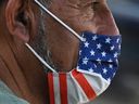 In this photo taken on July 19, 2021, a man wears an American flag face mask on a street in Hollywood, California, on the second day of the return of the indoor mask mandate in Los Angeles County due to a spike in COVID-19 cases.