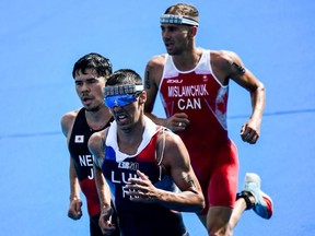 France's Vincent Luis (C), Japan's Kenji Nener (L) and Canada's Tyler Mislawchuk compete in the men's individual triathlon competition during the Tokyo 2020 Olympic Games at the Odaiba Marine Park in Tokyo on July 26, 2021.