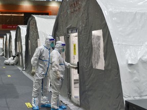 This photo taken on July 28 shows staff members checking a unit at a temporary "Fire Eye" laboratory used for COVID-19 testing at an exhibition centre in Nanjing.