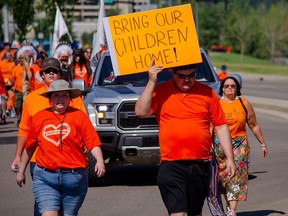 People arrive at Snye Point Park in Fort McMurray, Alta., at the end of a memorial walk honouring victims and survivors of the residential school system, on July 7, 2021.