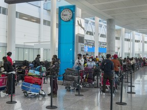 Passengers from New Delhi wait in long lines for transportation to their quarantine hotels at Pearson Airport in Toronto on Friday April 23, 2021. Flights from India and Pakistan to Canada have been suspended for 30 days.