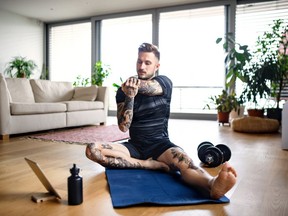 Front view portrait of young man with tablet doing workout exercise indoors at home.