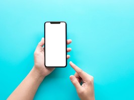 Female hand using smartphone with blank screen on color background