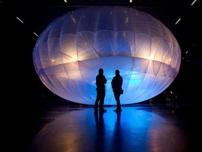 Visitors stand next to a high altitude WiFi internet hub, a Google Project Loon balloon.