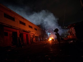 A woman walks past a pile of burning trash in Port-au-Prince, Haiti, July 18, 2021.