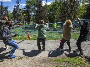 Supporters tear down a fence surrounding a homeless encampment at Trinity Bellwoods Park in Toronto, on June 22.