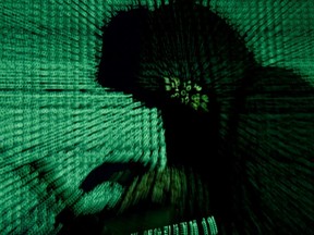 A man holds a laptop computer as cyber code is projected on him in this illustration picture taken on May 13, 2017.