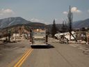 Ein Feuerwehrauto fährt am 9. Juli 2021 die Main Street hinunter, vorbei an beschädigten Gebäuden in Lytton, BC.