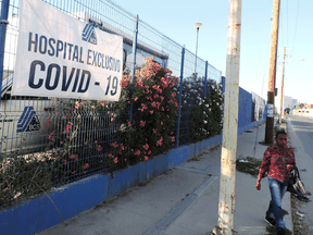 A woman walks by a banner reading 'Hospital exclusive for COVID-19' outside the Cabo San Lucas General hospital as the COVID-19 outbreak continues, in Los Cabos, Mexico, earlier this month.