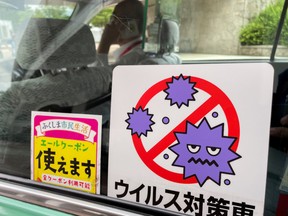 A COVID-19 sign is seen in a taxi outside the Azuma Baseball Stadium during the Tokyo 2020 Olympic Games softball tournament in Fukushima, Japan July 22, 2021.Picture taken July 22, 2021.